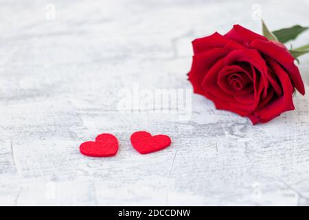 Zwei rote Herzen und rote Rose auf einem weißen Steingrund. Romantisches Geschenk zum Valentinstag. Liebe. Weichfokus. Speicherplatz kopieren. Draufsicht Stockfoto