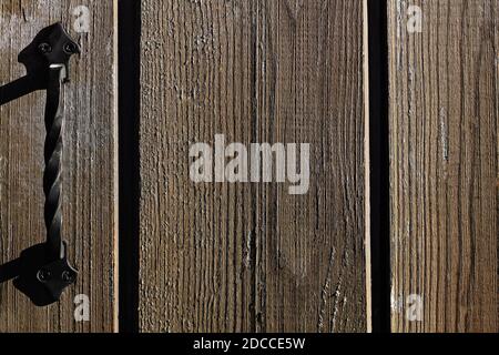 Türknauf aus Gusseisen an einer Holztür. Dunkelbrauner Holzhintergrund. Alte, schäbige Bretter. Zerkratzte Holzwand Stockfoto