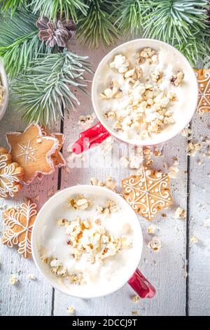 Popcorn Latte Kaffeebecher. Trendiges Heißgetränk, Latte mit gesalzenem Käse-Popcorn, mit winterlicher Weihnachtsdekoration, weißer Holzhintergrund-Kopierraum Stockfoto