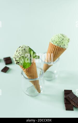 Kugeln Minzeis mit Schokoladenbröseln in Waffelkegel auf hellgrünem Hintergrund. Sommer erfrischende Wüste. Stockfoto