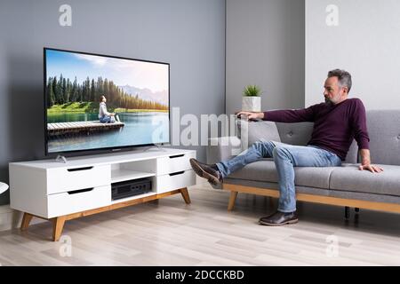 Älterer Mann Streaming und Film auf TV-Bildschirm Stockfoto