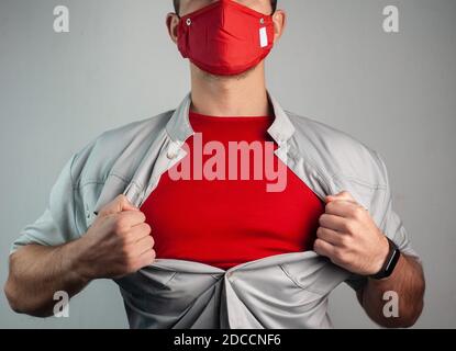 Superheld in einer medizinischen Maske reißt das Hemd auf seinem Brust Stockfoto