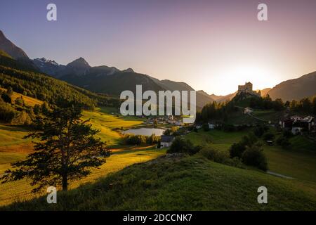 Die Sonne geht in den Bergen um Tarasp und seine Burg im Kanton Graubünden (Engadin) in der Schweiz unter. Stockfoto