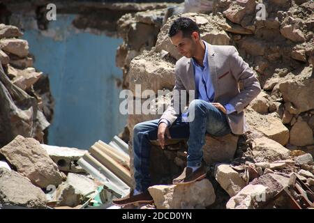 Taiz / Jemen - 13 Apr 2017 : EIN Mann aus dem Jemen sitzt an einem Haus, das im Krieg in Taiz, Jemen, zerstört wurde. Stockfoto