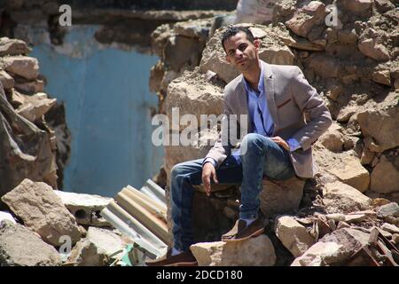 Taiz / Jemen - 13 Apr 2017 : EIN Mann aus dem Jemen sitzt an einem Haus, das im Krieg in Taiz, Jemen, zerstört wurde. Stockfoto