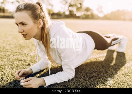 Perfektes Board. Junge schöne Frau in Sportkleidung, die eine Planke macht, während sie im Freien steht Stockfoto