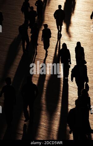 Blick Auf Menschen, Die Während Des Sonnentags Mit Schatten Auf Dem Fußweg Spazieren Stockfoto