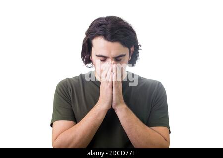 Porträt von depressiven jungen Mann hält die Hände zusammen als Gebet, Augen geschlossen, Kopf nach unten über weißem Hintergrund. Verzweifelter Kerl, der um Hilfe betet. Konzept Stockfoto