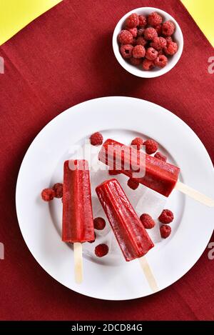 Himbeer-Eis-Eiszapfen auf weißem Teller. Leckeres Sommerdessert. Draufsicht, flach liegend Stockfoto