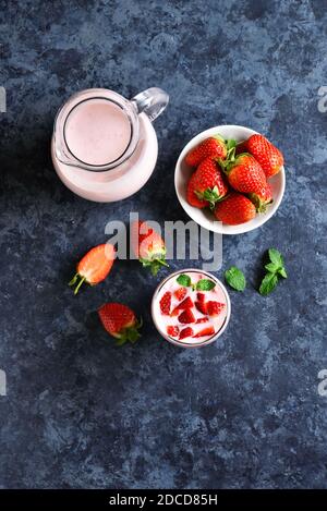 Erdbeerjoghurt mit frischen Beeren auf blauem Steingrund mit freiem Textbereich. Gesundes Essen- und Getränkekonzept. Draufsicht, flacher Lay Stockfoto