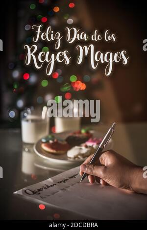 FELIZ DIA DE LOS REYES MAGOS, spanische Übersetzung von GLÜCKLICHEN WEISEN TAG: Kind writting a Letter with the words 'QueridosReyes magos' Stockfoto