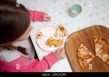 Junges Mädchen essen Huhn Nuggets und Pizza Stockfoto