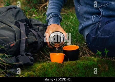 Trinken Sie Tee aus Thermoskannen während der Wanderung. Mann Hand Gießen heißen Tee aus Thermoskannen Stockfoto