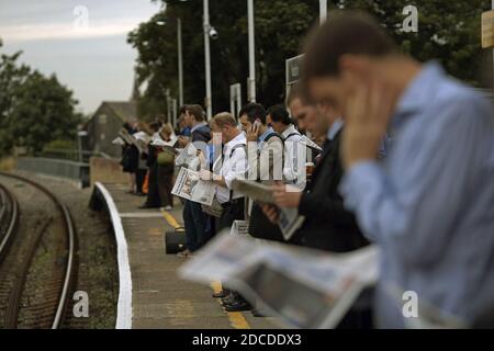 GROSSBRITANNIEN / England / Kingston upon Thames /Pendler warten auf dem Bahnsteig im Bahnhof Norbiton. Pendeln Sie nach London. Lesen Sie Papier. Stockfoto