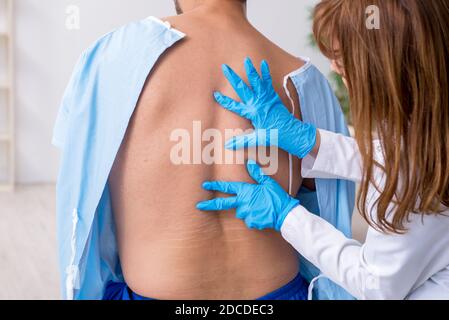 Junger verletzter Mann, der einen weiblichen Arzt aufsucht, Chiropraktiker Stockfoto