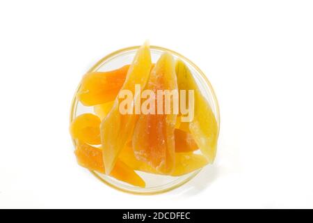 Gelbe kandierte Melonenscheiben in einer Glasvase auf weißem Hintergrund, Draufsicht in einer Glasvase auf weißem Hintergrund, Draufsicht. Stockfoto