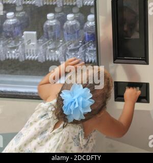 Kleines Mädchen spielt in einem Wasserautomaten Stockfoto