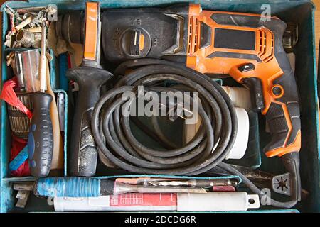 Draufsicht auf gebrauchte Werkzeugkiste, elektrische Bohrmaschine, Bohrer, Schraubendreher und Gewindestifte Stockfoto