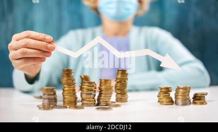 Frau hält einen Pfeil nach unten über den Stapel von Münzen. Stockfoto