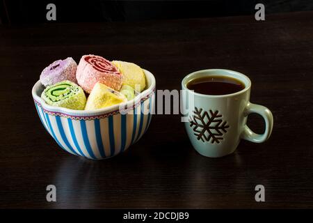 Türkische Freude an einer Porzellanvase und einer Tasse Kaffee auf schwarzem Hintergrund. Stockfoto