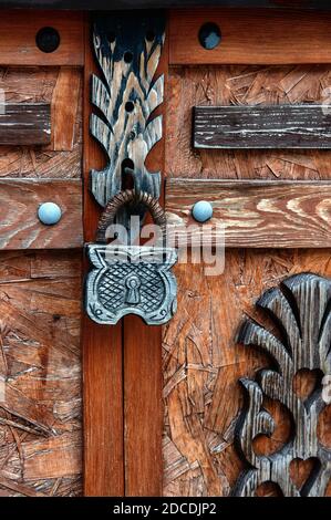 Geschlossene Holzschlosstür Sicherheit. Ein stilisiertes Holzschloss hängt an einer mit Holz verzierten Tür. Stockfoto