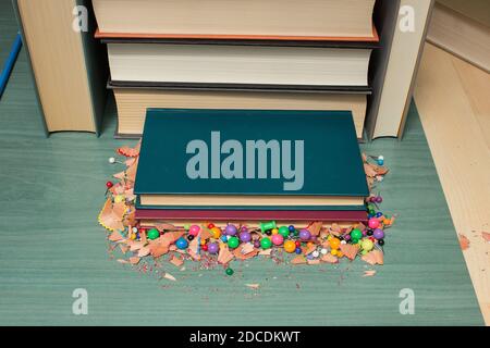 Lehrbücher auf einem Holztisch mit Daumenheften und Spuren von Buntstiften. Stockfoto