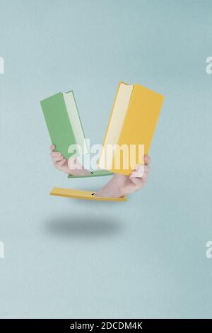 Zwei von Händen gehaltene Bücher schweben in der Luft dicht beieinander, als ob sie tanzen. Konzept „gemeinsam lesen“. Stockfoto