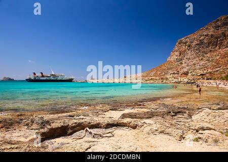 2019, 4. JUNI: - GRIECHENLAND, DIE INSEL KRETA, BALOS - die Burg auf dem Gipfel des Berges und die Menschen am Strand darunter. Stockfoto