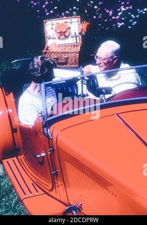 Rentnerpaar genießen Picknick in ihrem klassischen MG Roadster, USA Stockfoto