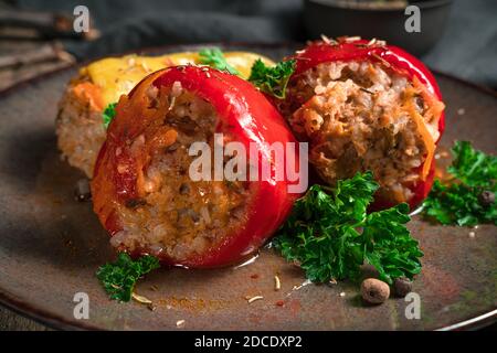 Pfeffer mit Fleisch, Reis und Karotten mit Petersilie und Gewürzen auf einem braunen Teller. Stockfoto