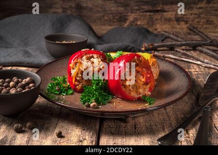 Gefüllte Paprika in einem Teller auf einem hölzernen braunen Hintergrund. Stockfoto