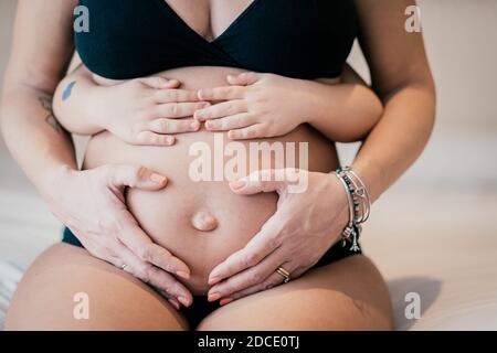 Nahaufnahme Bild der schwangeren Frau und ihr Baby halten Ihr Bauch - Baby hält den Bauch seiner schwangeren Mutter - schwangere Frau und ihr Baby holdin Stockfoto