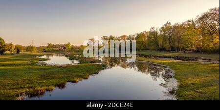 Ruhiger Fluss entlang eines Wanderweges in einer holländischen Farmlandschaft während des Sonnenuntergangs. Es befindet sich in der Nähe des kleinen Viertels Tusveld in der Nähe von Almelo Stockfoto