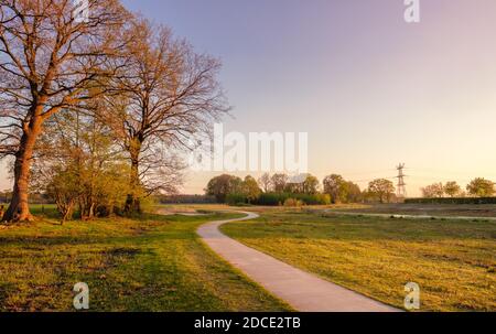 Weitläufige Fahrradstrecke in einer holländischen Bauernhofläandschaft bei Sonnenuntergang. Es befindet sich in der Nähe des kleinen Viertels Tusveld in der Nähe der Stadt Almelo Stockfoto