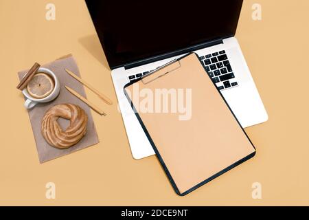 Laptop, Kuchen, Tasse Tee und Lebenslauf Blatt auf dem pastellorange Tisch, Draufsicht. Stockfoto