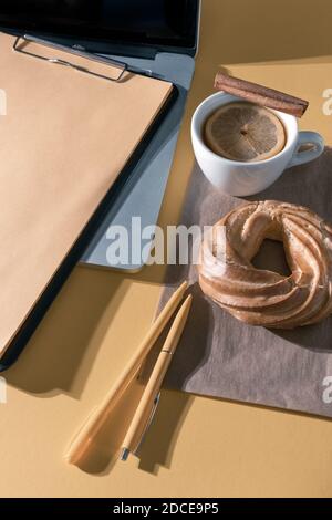 Laptop, Stifte, Kuchen, Tasse Tee und Lebenslauf Blatt auf dem pastellorangen Tisch, Draufsicht. Stockfoto