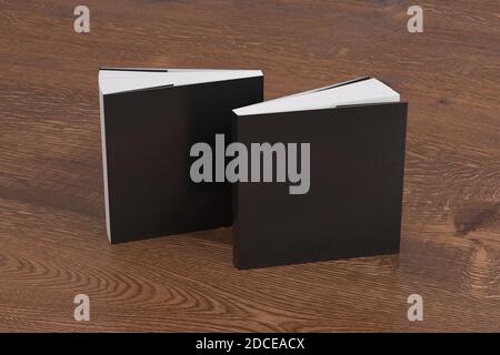 Zwei quadratische schwarze Mockup-Bücher mit Softcover oder Taschenbuch stehen auf dem hölzernen Hintergrund. Leere vordere und hintere Abdeckung Stockfoto