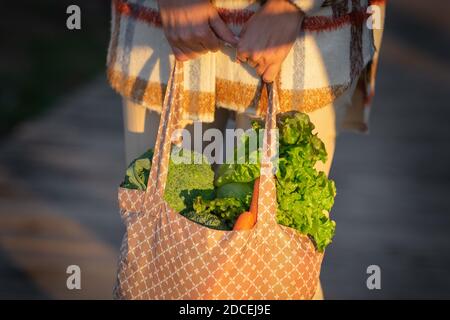 Junge Frau hält Öko wiederverwendbare Textil-Lebensmittelbeutel mit Gemüse. Pflanzliche Ernährung Einkaufen. Sauberes veganes Esskonzept. Zero Waste Konzept Stockfoto