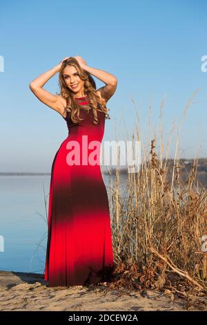 Porträt einer Frau am Strand in einem langen Rot Und schwarzes Kleid Stockfoto