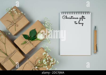 Weihnachten flach legen minimale Zusammensetzung mit Holzstift, Notizbuch und Geschenk-oder Geschenkschachteln, mit Kraftpapier auf grauem Hintergrund mit Copyspace verpackt Stockfoto