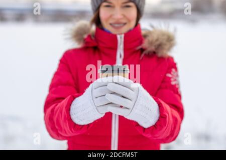 Eine junge Frau hält im Winter ein Glas heiß Kaffee oder Tee Stockfoto