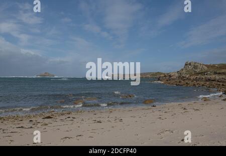 Gimble Porth Strand mit Round Island Leuchtturm in der Ferne Und ein wolkiger blauer Himmel Hintergrund auf der Insel Tresco auf den Scilly-Inseln Stockfoto