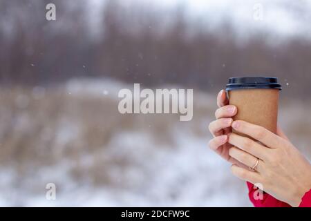 Eine junge Frau hält im Winter ein Glas heiß Kaffee oder Tee Stockfoto