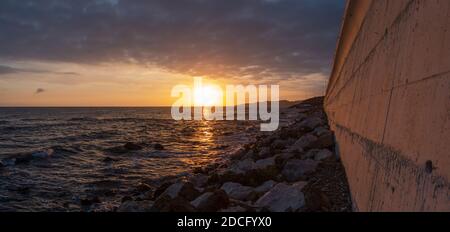 Betonmauer entlang der Küste, mit Autobahn N340 oben, Sonnenuntergang, El Faro de Calaburras, Andalusien, Spanien. Stockfoto