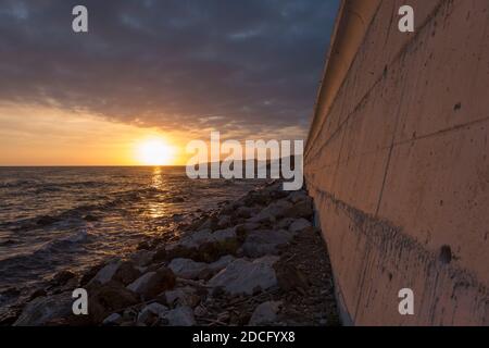 Betonmauer entlang der Küste, mit Autobahn N340 oben, Sonnenuntergang, El Faro de Calaburras, Andalusien, Spanien. Stockfoto