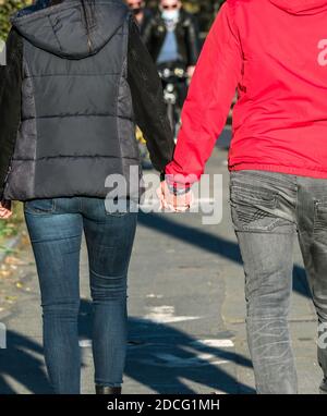 Rückansicht eines jungen Paares, das die Hände auf der Straße hält. Stockfoto