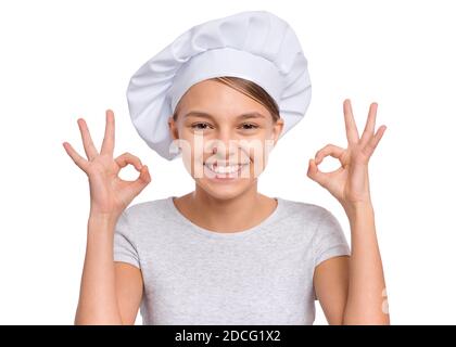 Happy Teenager-Mädchen trägt Chef Hut mit Emotionen, die Zeichen mit Händen, isoliert auf einem weißen Hintergrund. Stockfoto