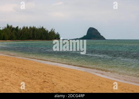 Strand auf Secret Island, Oahu, Hawaii, mit Blick auf die Insel Mokoli'i (früher bekannt als der veraltete Begriff „Chinaman's hat“) auf der anderen Seite der Bucht Stockfoto