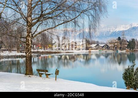 Zell am See im Winter. Blick von der Esplanade über den Zeller See in die Stadt Prielau. Idyllische Szene mit Bank, Birke, Schnee und nebligen Berg in der Alpenstadt Stockfoto