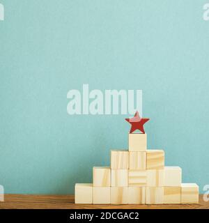 Roter Stern auf Holzblocktreppe mit grünem Hintergrund. Business Development, Growth, Success Concept Stockfoto